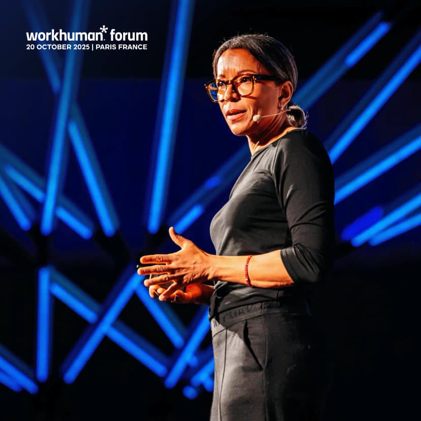 A speaker presenting at the Workhuman Forum in Paris, France, on October 20, 2025. The individual is gesturing with their hands while wearing a black outfit and glasses. Bright blue lights form a dynamic backdrop. The image includes the event title and date prominently displayed.