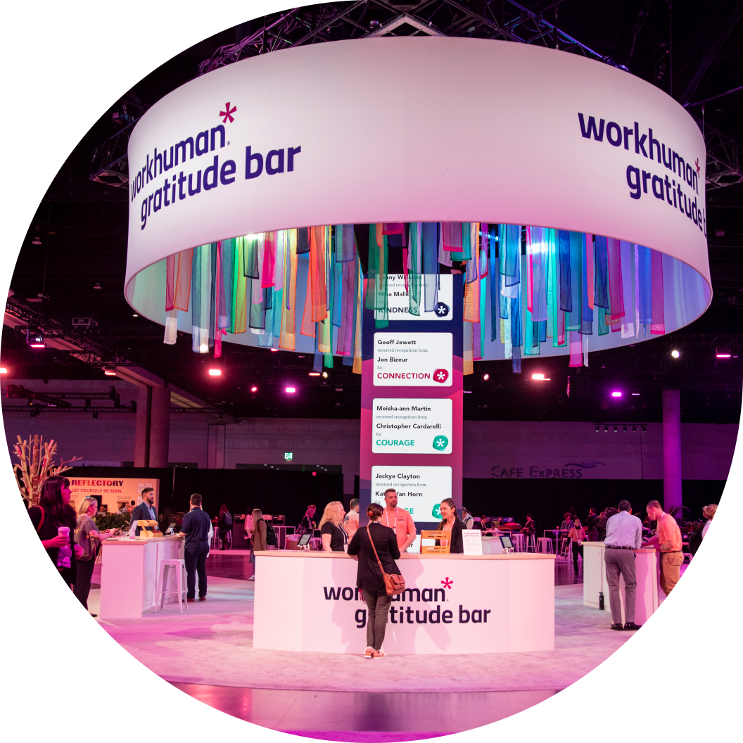 A vibrant Gratitude Bar at the Workhuman event, featuring colorful hanging ribbons. Attendees are mingling in the background, and a display lists individuals recognized for Connection and Courage, with names like Geoff Jewett, Jon Bizeur, Meisha-ann Martin, and Christopher Cardarelli.